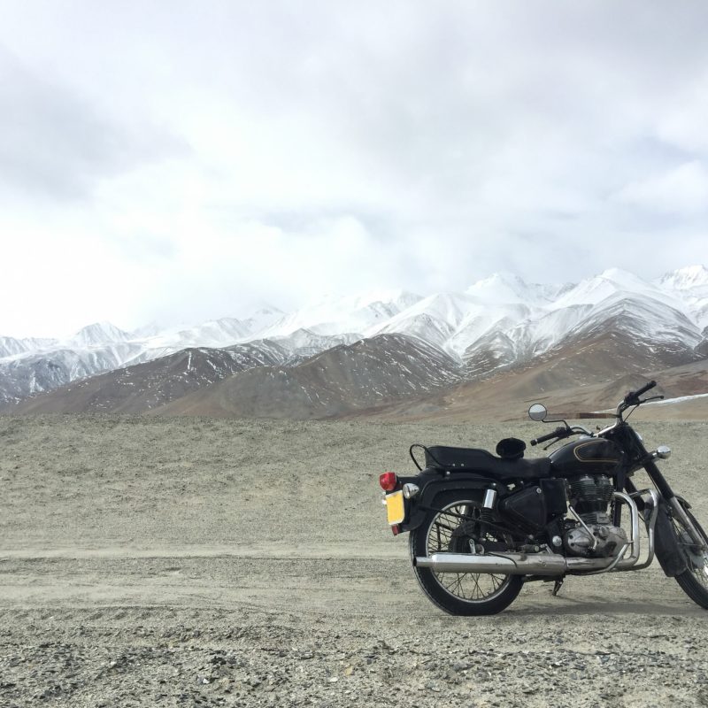 Motorcycle alone enduro traveler with suitcases standing on rocky plateau in cloudy weather on the background of endless mountain steppe Plateau Ukok Altai mountains Siberia Russia.